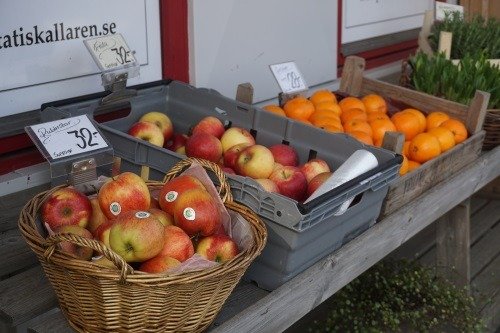 Äpplen och apelsiner i lådor utanför butiken